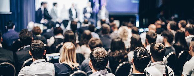 Viele Personen folgen aufmerksam einem Seminar