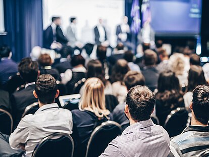 Viele Personen folgen aufmerksam einem Seminar