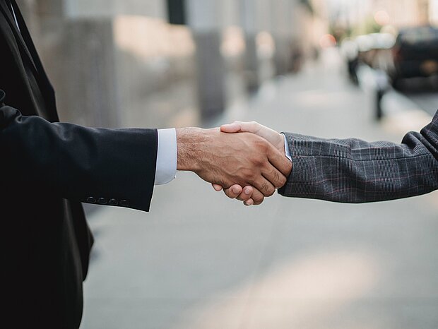Handshake auf der Straße von einem Mann und einer Frau in Businesskleidung