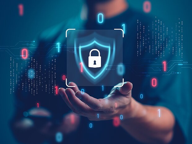  Im Hintergrund ist ein Mann zu sehen, der ein Schloss in der Hand hält, welches für IT-Sicherheit steht. Links und rechts von ihm sind Zahlen, wobei die 0 in Rot und die 1 in Blau dargestellt sind.