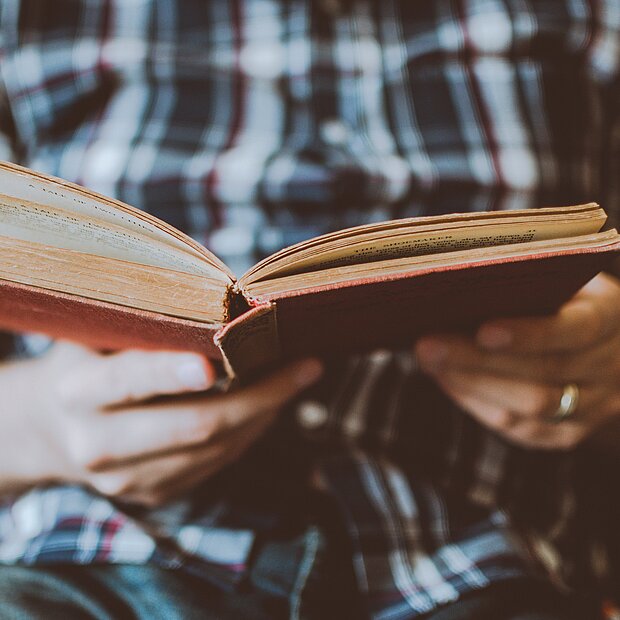 Ein Mann hält eine altes Buch in den Händen und liest